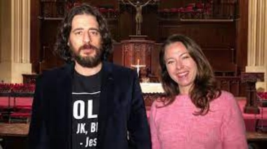 Picture of Jonathan Roumie in a blue suit  with his rumored wife Hannah Vanorman